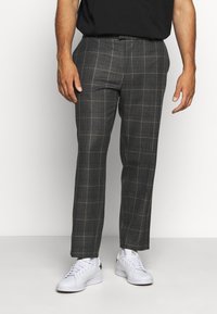 Grå rutiga byxor med skräddarsydd passform, med ett subtilt rutig mönster, tillverkade av vävd tyg. Matchade med vita sneakers.