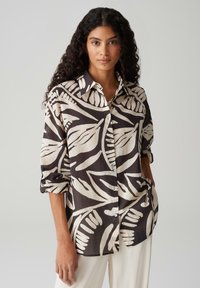 Camicia bottonata nera e panna con un grande motivo a foglia; tessuto leggero con una vestibilità comoda e maniche arrotolate.