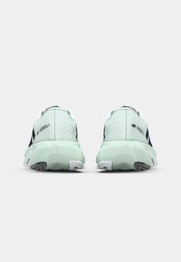 Running shoes featuring a light mint upper, textured fabric, black accents, and a distinctive geometric sole design in light green and white.