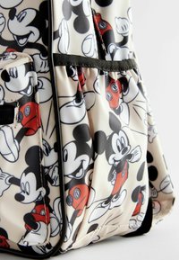 Sac à dos avec une surface brillante et texturée, orné d'un imprimé coloré de Mickey Mouse. Les couleurs dominantes sont le noir, le blanc et le rouge, avec des bretelles ajustables.