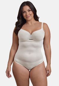 Shapewear beige senza cuciture con reggiseno integrato. Texture liscia, spalline regolabili e dettagli in pizzo sui bordi. Stile pantaloni a shorts con copertura totale.