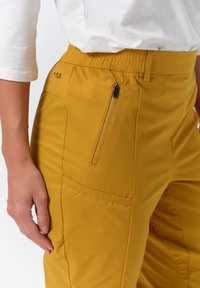 Gula, lätta utomhusbyxor med elastisk midja. Har en löstagbar sidoficka med dragkedja och en ytterligare ficka med klaff. Slät textur.
