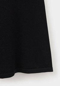 Partie de l'ourlet d'une jupe en maille noire montrant la texture du tissu et un bord net sur fond blanc.
