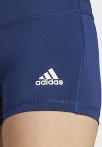 Pantaloni sportivi blu navy realizzati in tessuto morbido, con logo Adidas bianco sul lato. Presentano cuciture piatte e un design aderente.