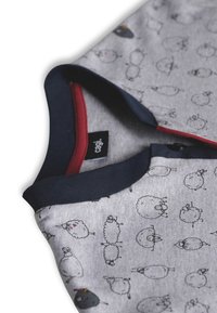 Pigiama grigio per bambini con illustrazioni di pecore in bianco e nero, colletto blu navy, scollatura interna rossa e bottoni a pressione neri.