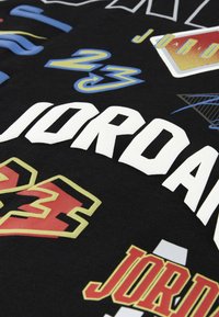 Sort stof med farverige Air Jordan-tekst og tallet 23-logoer i forskellige skrifttyper og stilarter.