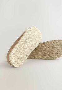 Shoe indlægssåler med en tekstureret beige overflade og glatte kanter, der har en tyk skummulp til polstring og støtte.