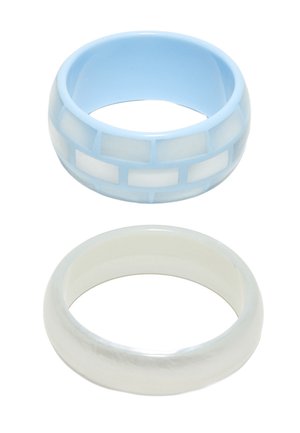 Deux anneaux lisses et brillants : l’un bleu clair avec des incrustations blanches rectangulaires, l’autre blanc nacré uni, tous deux arrondis et larges.