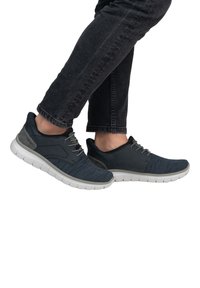 Baskets de sport pour hommes en bleu marine avec une tige en tricot texturé, des accents gris et une semelle blanche rembourrée. Design à lacets.