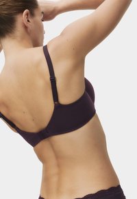 Mørkelilla bh med justerbare stropper, sømløst design og lukning med hægter. Blødt stof med få pyntedetaljer. Sidder under skulderen.