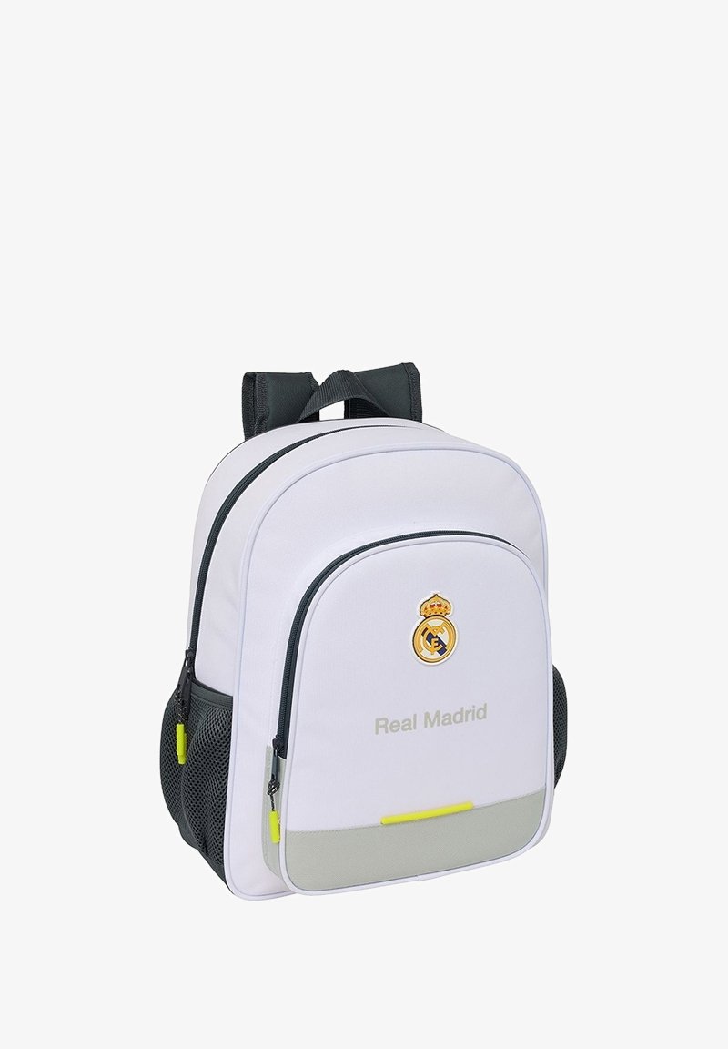 Sac à dos blanc et gris du Real Madrid avec des bretelles noires, une poche zippée à l'avant, des poches latérales en mesh et des tirettes de fermeture éclair jaunes.