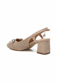 Zapato slingback de ante beige con punta afilada, acento decorativo de strass y un tacón bloque apilado. Cuenta con una correa en la parte posterior.