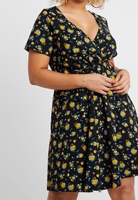 Black floral wrap dress featuring yellow roses and blue flowers, short sleeves, a V-neck, and a cinched waist with a flared skirt.