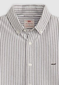 Bjela košulja s dugim rukavima i uskim sivim prugama, izrađena od pamuka, s klasičnom kragnom i malim izvezenim Levi's logotipom na prsima.