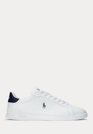 Baskets blanches basses avec patch bleu marine au talon, design à lacets et logo Polo Ralph Lauren sur le côté et la semelle.