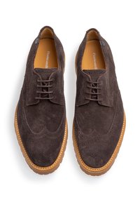 Zapatos de ante marrón con un diseño de puntera con alas, que cuentan con detallados perforaciones de brogue y una suela de goma en contraste. Cierre frontal con cordones.