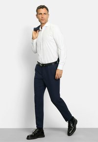 Weißes gemustertes Hemd, marineblaue Hose, schwarzer Gürtel und glänzende schwarze Schuhe. Slim-Fit-Design mit Knopfverschluss und langen Ärmeln.