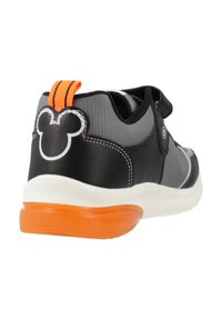 Sneaker nera e grigia con una tomaia testurizzata, dettagli arancioni, suola in gomma e un emblema di Topolino facilmente riconoscibile sul tallone.