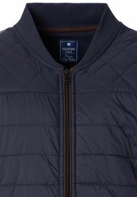 Marineblauer gesteppter Bomberjacke mit ribbeltem Kragen, Frontreißverschluss und braunen Akzenten. Das Material wirkt glatt mit einer gepolsterten Textur.