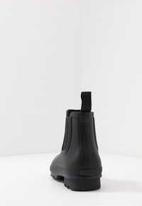Black rubber ankle boots with ribbed texture, pull tab at the heel, and a chunky sole for traction. Smooth finish, suitable for wet conditions.
