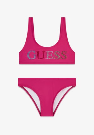 Bañador de dos piezas de color rosa brillante con parte superior de cuello redondo que presenta letras "GUESS" en piedras de colores y braguitas a juego.