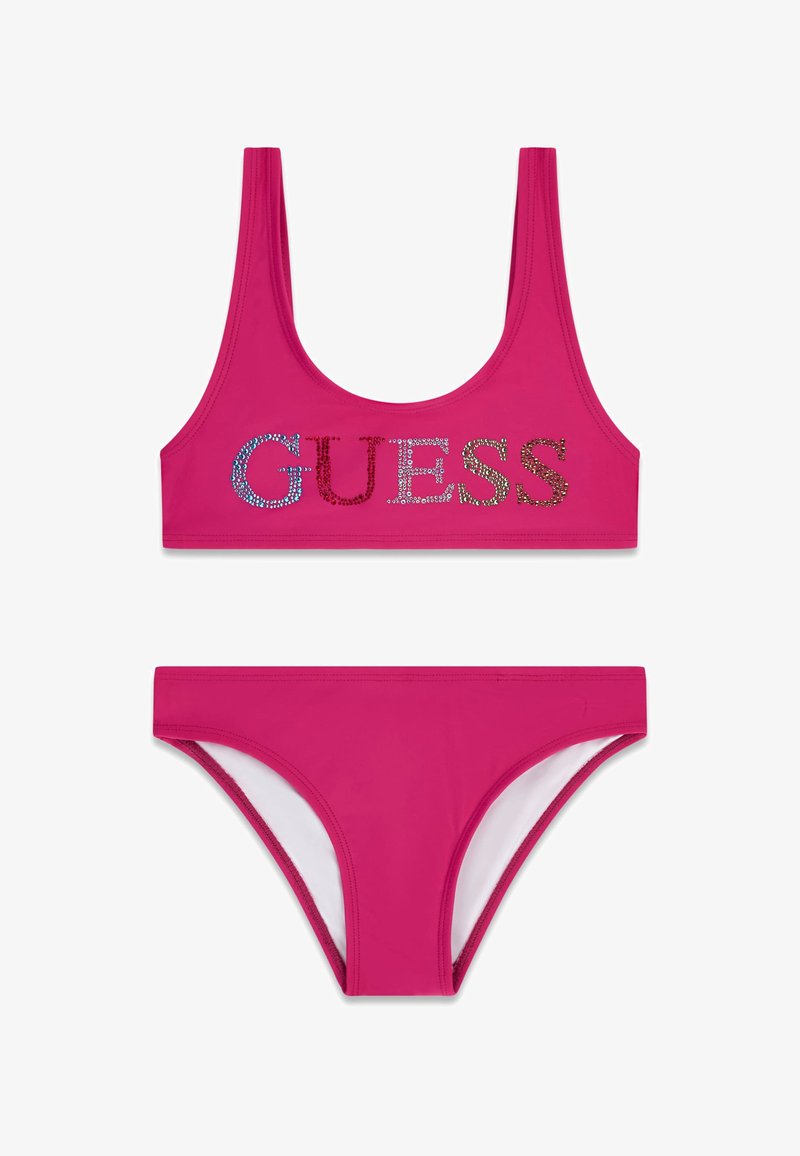 Maillot de bain deux pièces rose vif avec un haut à encolure dégagée orné de lettres "GUESS" en strass multicolores et un bas de bikini assorti.