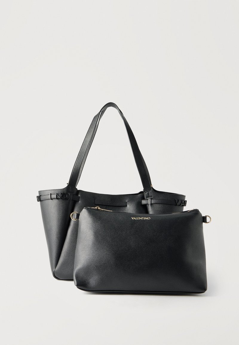 Δύο μαύρες δερμάτινες τσάντες Valentino, μία tote με διπλές λαβές και μία μικρότερη τσαντούλα με φερμουάρ, σε λευκό φόντο.