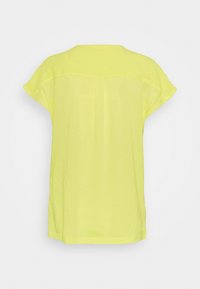 T-shirt giallo a maniche corte con vestibilità morbida, dotato di scollo rotondo e dettaglio cucitura centrale sul retro. Texture liscia.