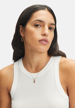 Oorbellen met een rechthoekig ontwerp in roségoud metaal, gedragen met een geribbelde witte top. Een bijpassende hangende ketting is ook zichtbaar.