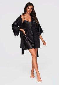 Abito in satin nero con pizzo, abbinato a una veste kimono, caratterizzato da maniche larghe e design aperto davanti. Texture liscia, lunghezza al ginocchio.