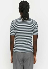 Kurzarm, tailliert, navy- und weißgestreiftes Baumwoll-T-Shirt mit Rundhalsausschnitt, getragen mit grauen Hosen, von hinten betrachtet.