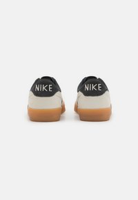 Crni i krem Nike tenisice s nubukom i gumenim materijalom, s dvostrukim 'NIKE' brendingom na peti i gumenim potplatom.