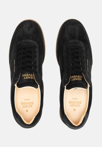 Schwarze Wildledersneaker mit passendem Schnürsenkel, Gummisohle und geprägtem Branding an Zunge und Ferse. Glattes Innenfutter.