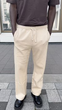 Beige sporta bikses ar uzsaites jostu, ar sānu kabatām un brīvu piegriezumu, kombinētas ar melniem apaviem ar masīvu zoli.