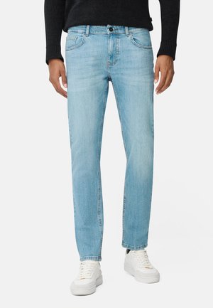 Lyseblå denimjeans med lige pasform, fem lommer og knaplukning. Bæres med hvide træningssko.