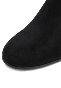 Čierne semišové členkové topánky s okrúhlym špičkou, hladkým povrchom a flexibilnou gumovou podrážkou. Vyznačujú sa čistým dizajnom bez viditeľného kovania.