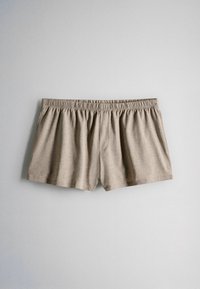Pantalones cortos beige de tela suave con cintura elástica, mostrados planos sobre un fondo gris claro.