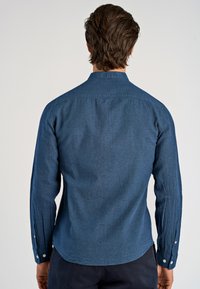 Camicia a maniche lunghe blu scuro con colletto, dotata di polsini con bottoni e un tessuto testurizzato. Vestibilità tailored con orlo curvo.