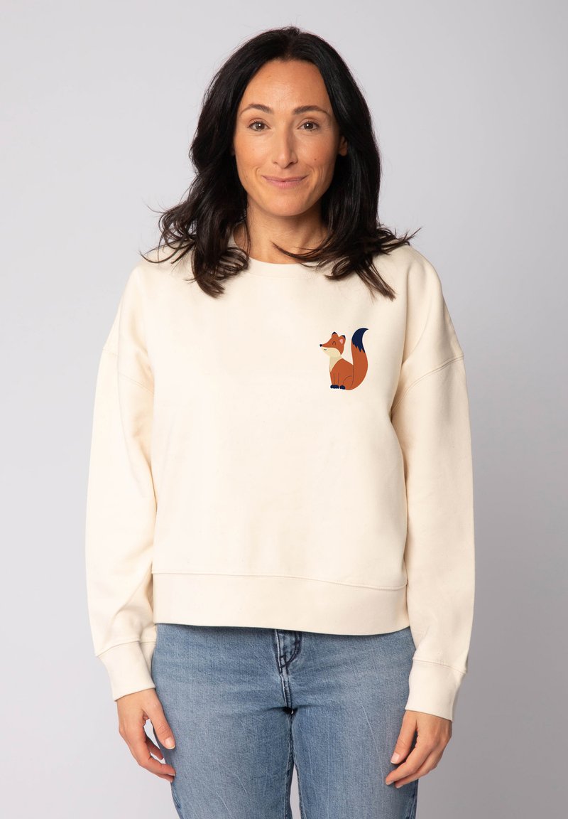 Crèmewitte sweatshirt met een ontspannen pasvorm, met een afbeelding van een vos in oranje en blauwe accenten op de linkerborst. Zachte stoftextuur.