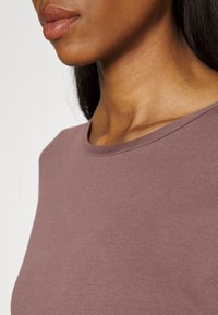 Lila crew-neck topp i mjukt, slätt tyg med en figurvänlig passform och en liten lyster på ytan.