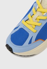 Μπλε αθλητικό παπούτσι με πλέγμα σε όλο το πάνω μέρος, κίτρινες κορδόνια και πορτοκαλί λεπτομέρειες. Ομαλή σόλα από καουτσούκ με μαύρο σχέδιο πέλματος και υφή.