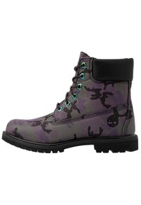 Botas de tobillo con camuflaje púrpura y acentos en negro, con cordones verdes, una superficie texturizada, suela de goma y detalle del logo en la parte trasera.