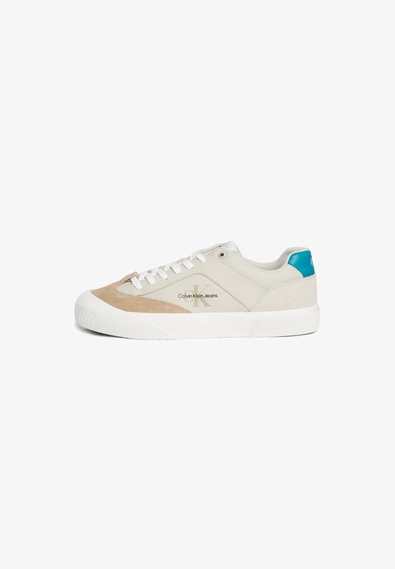 Sneakers z beżowym zamszem i szarym płótnem na wierzchu, białą gumową podeszwą i niebieskim akcentem na pięcie; mają białe sznurówki i szczegóły z logo.