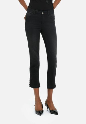 Jeans neri tagliati con una vestibilità slim, dettagli all'orlo e design tradizionale a cinque tasche. Abbinati a scarpe nere con tacco alto.