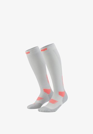Knee-high compression socks in light gray with bright pink accents, featuring a ribbed texture and striped patterns on the foot and calf sections.