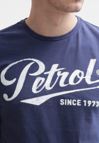 Námořnická modrá bavlněná tričko s velkým bílým logem "Petrol" a textem "SINCE 1973", s kulatým výstřihem a měkkou texturou.