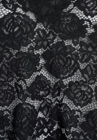 Tessuto di pizzo nero con un motivo floreale composto da rosette in rilievo, bordi scallop intricati e uno sfondo in rete traslucida.