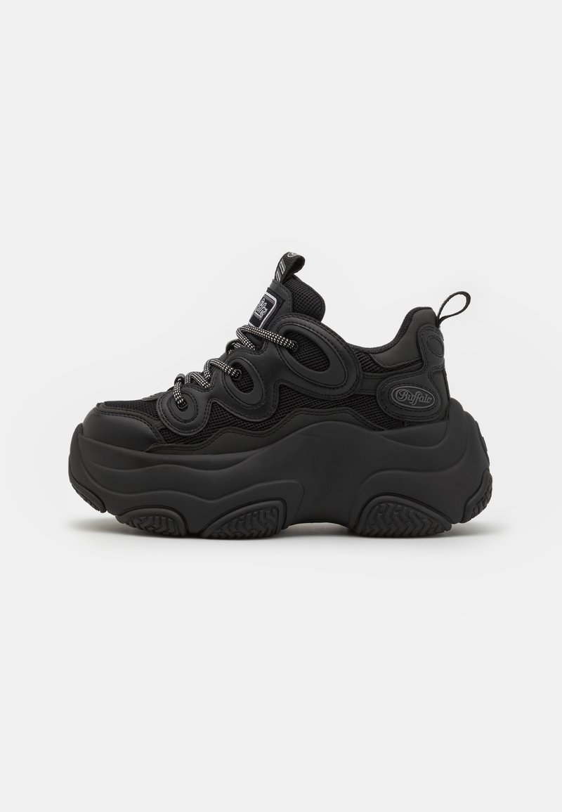 Black sneaker with a chunky design, featuring a textured upper, mesh panels, and thick rubber sole. Reflective laces and branding details visible.