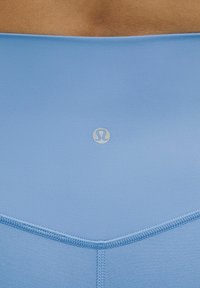 Svetlo modra športna elastika z gladko teksturo, srečena z diagonalnim šivom in majhnim logotipom na sredini.