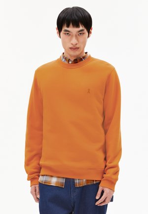 Oranje sweatshirt met ronde halslijn, lange mouwen en een klein logo. Draagt over een geruite blouse en gecombineerd met denim jeans.